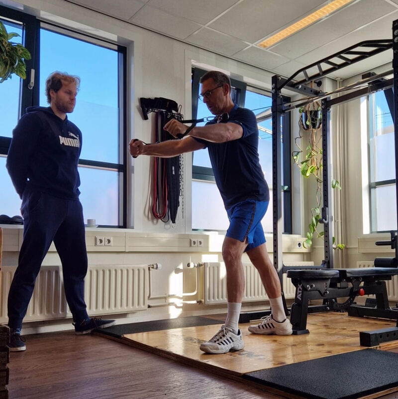 Othmar Versteeg begeleidt een cliënt tijdens krachttraining in de studio